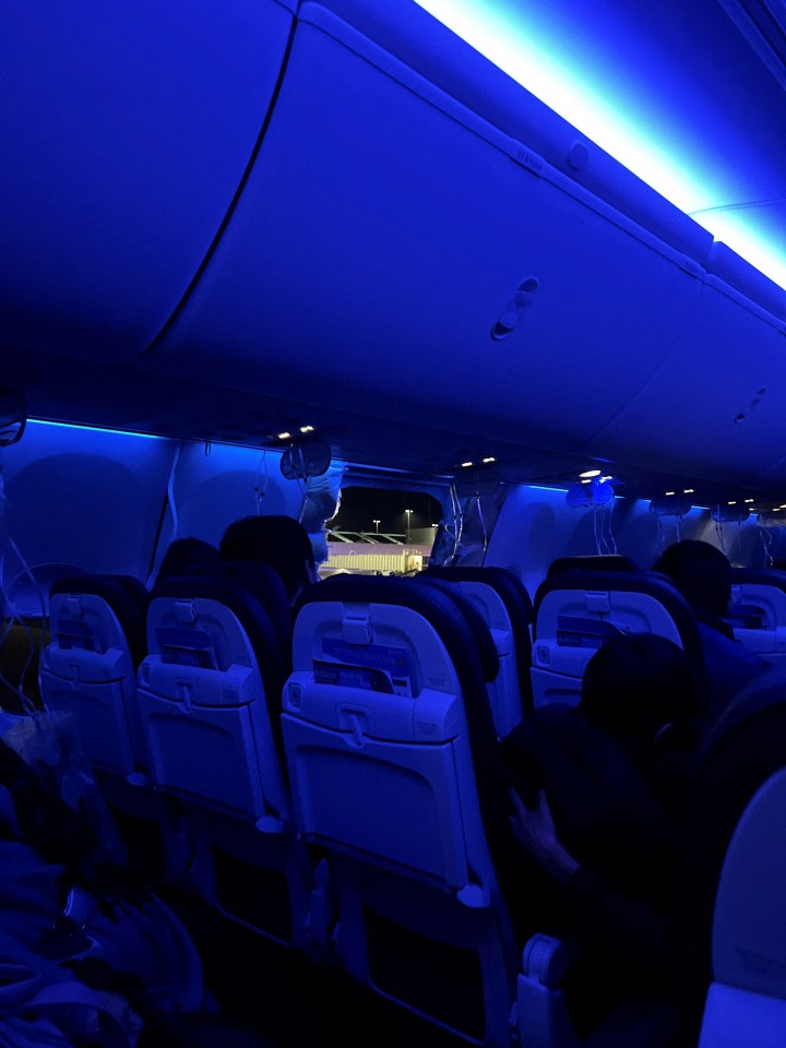 People sit on the Alaska Airlines plane next to the missing door