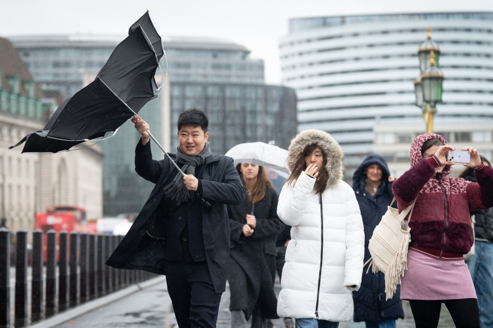 A person’s umbrella is blown inside out during heavy rain on Westminster Bridge today