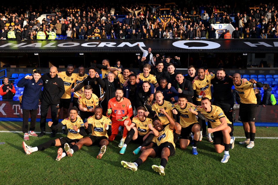 Maidstone players and coaching staff celebrate on the pitch