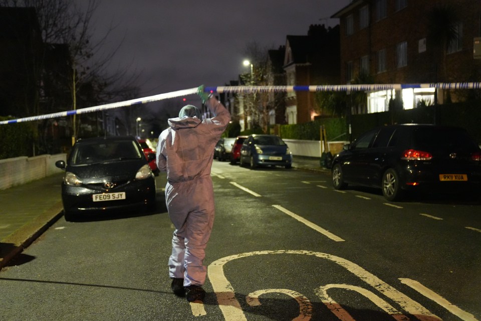 A forensic officer slips under the police cordon