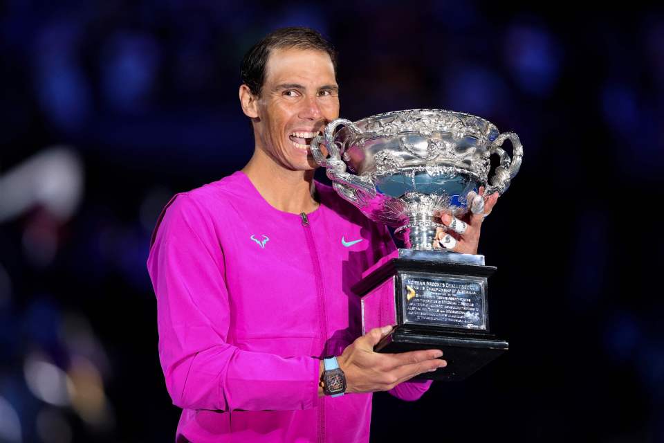 a man in a pink shirt is holding a trophy