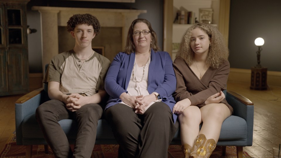 a woman sits on a couch with two children