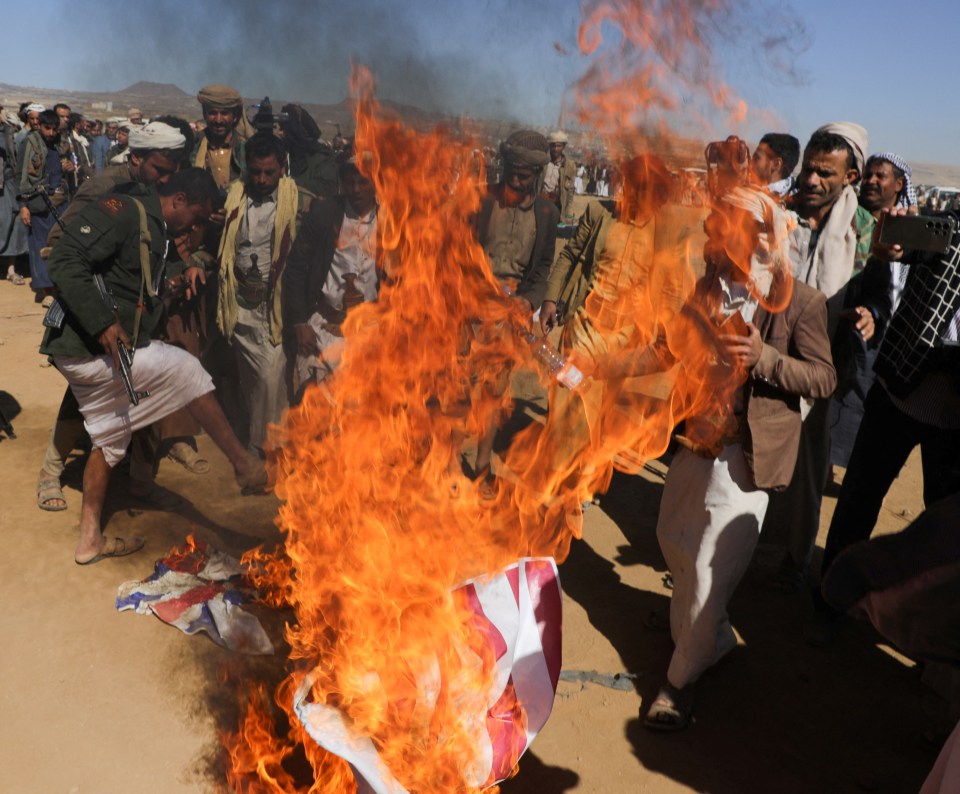 Tribal Houthi supporters group burn US and British flags during a protest against recent strikes near Sanaa in Yemen