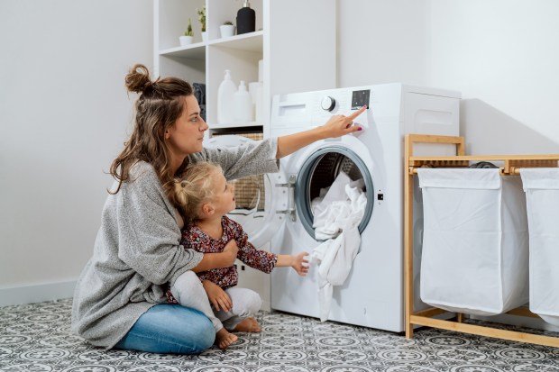 a woman and child are looking at a washing machine