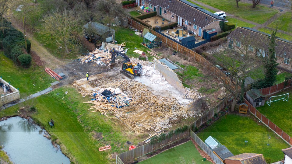 Workers sweep away the rubble at the spa complex at Captain Tom Moore's family home in Bedfordshire today