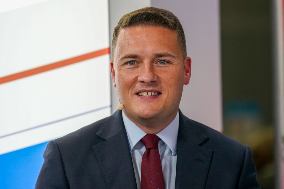 a man in a suit and tie stands in front of a microphone