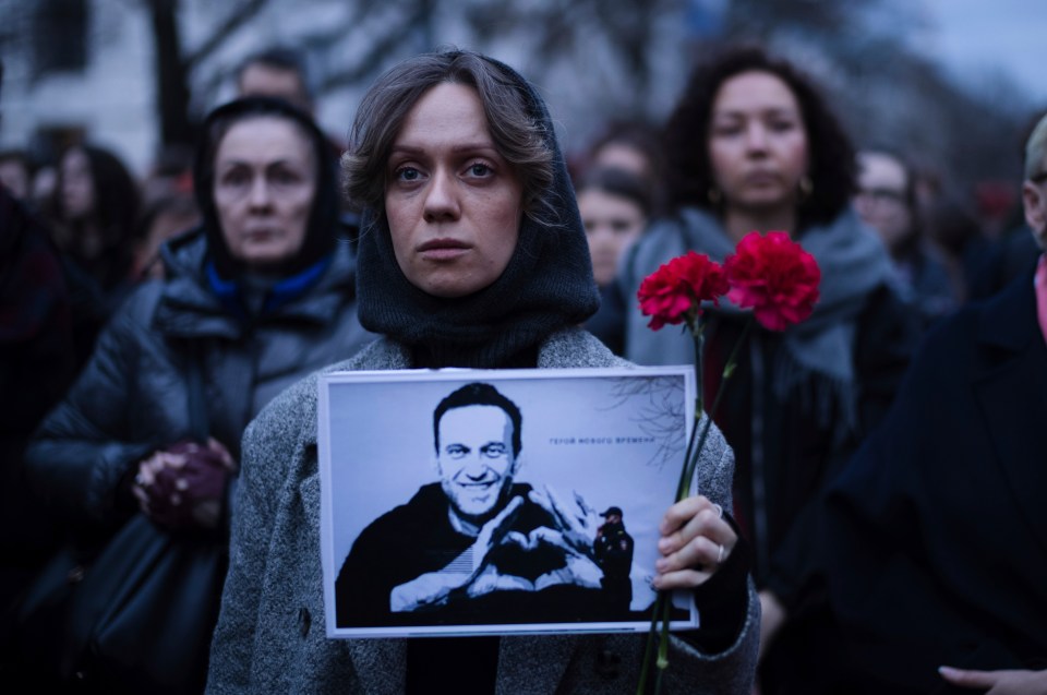 A woman holds flowers and a portrait of Navalny in front of the Russian embassy in Berlin, Germany