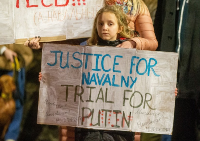 A girl holding up a sign at the Russian embassy in London