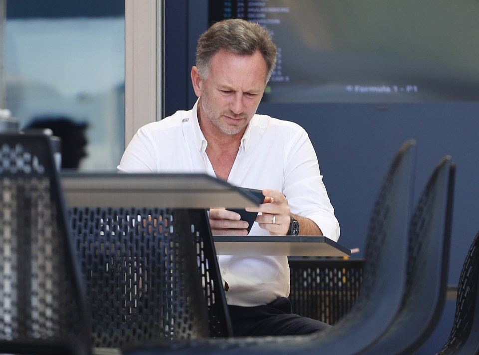 Horner looks at his phone intently from the sidelines of the F1 Paddock during day two of testing in Bahrain last Friday