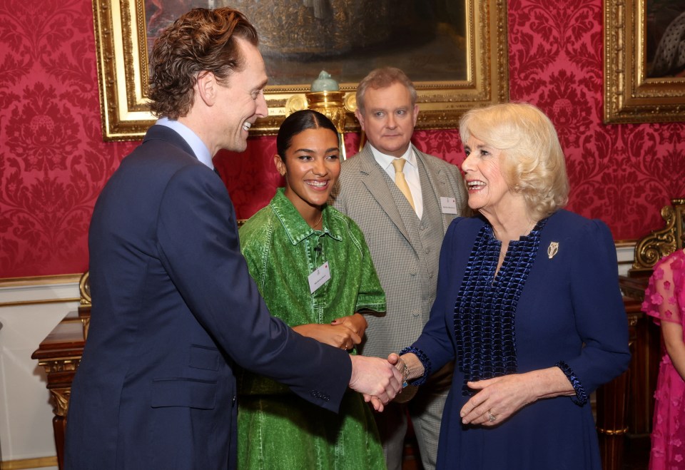 Queen Camilla shakes hands with Tom Hiddleston at the bash for BBC’s 500 Words competition