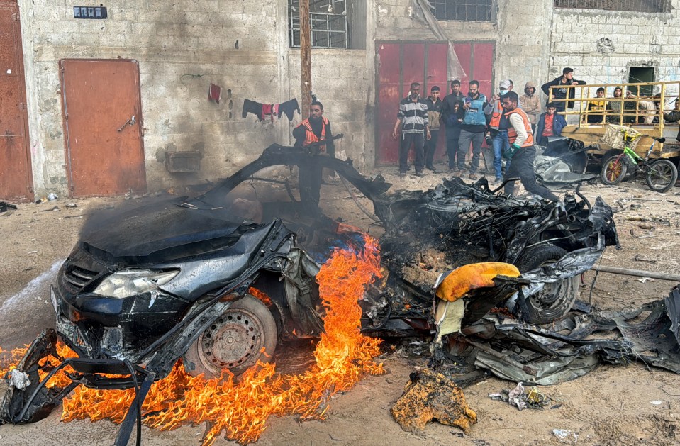 A firefighter extinguishes a burning car hit by an early Israeli strike in Rafah