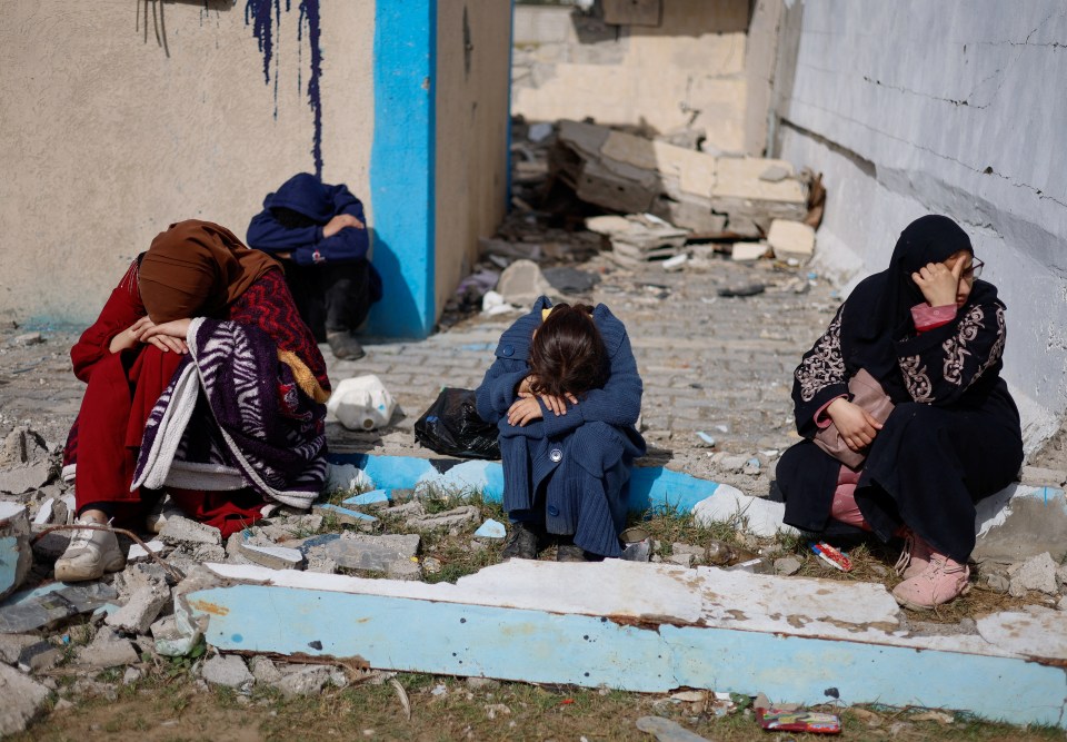 People rest next to damaged buildings, as Palestinian arrive in Rafah after they were evacuated from Nasser hospital in Khan Younis due to the Israeli ground operation, amid the ongoing conflict between Israel and Hamas, in the southern Gaza Strip, February 15, 2024. REUTERS/Mohammed Salem