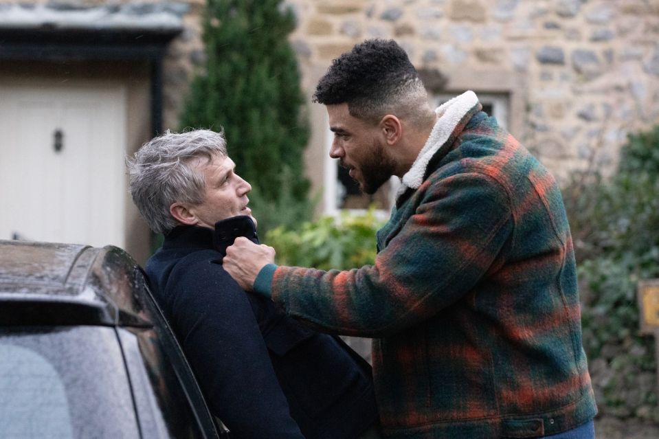 two men are standing next to each other in front of a car