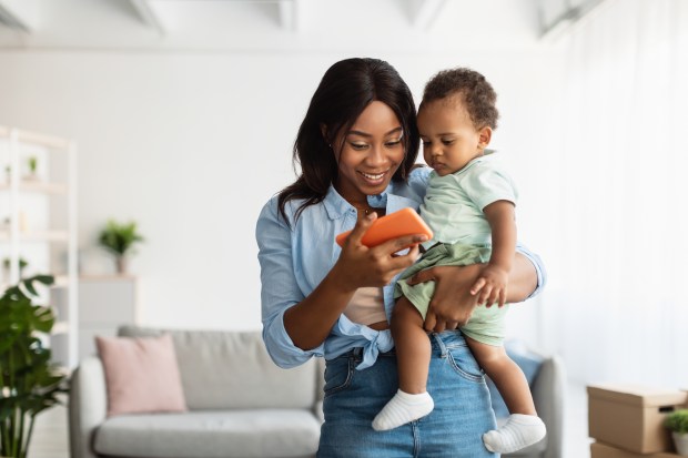 a woman is holding a baby and looking at a cell phone