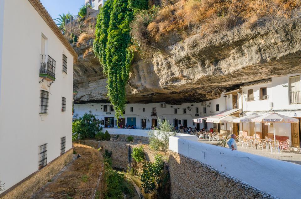 The town's main street sits beneath an overhang of rock next to a river