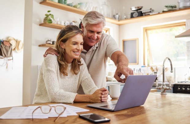 a man and woman are looking at a laptop together