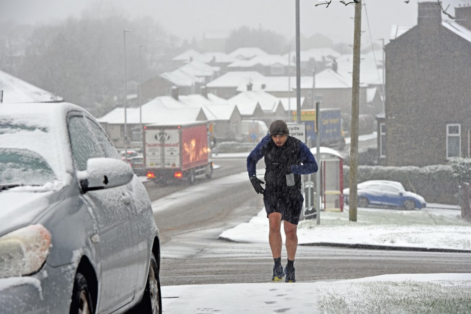 A jogger in the Bradford, West Yorkshire, runs through the snow today