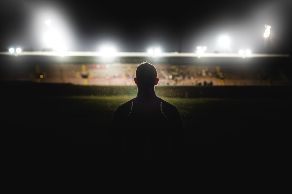 A young muscular Caucasian male walking in the rain at night in front of a stadium with stadium floodlights spotlights towards the competition near Cape Town South Africa