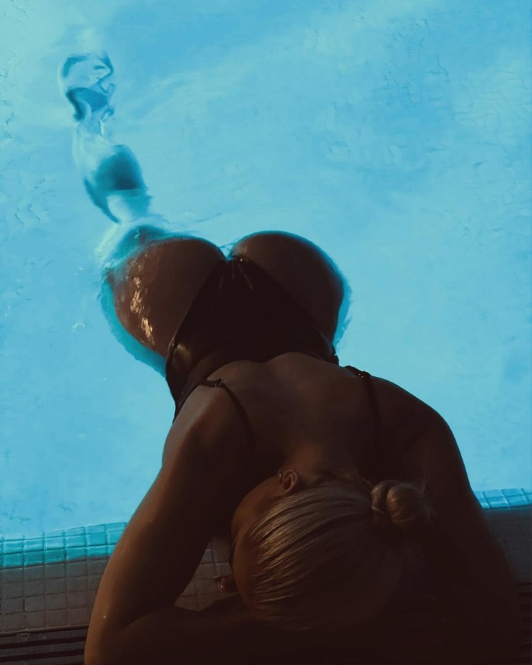 a woman in a black bikini is laying in a pool