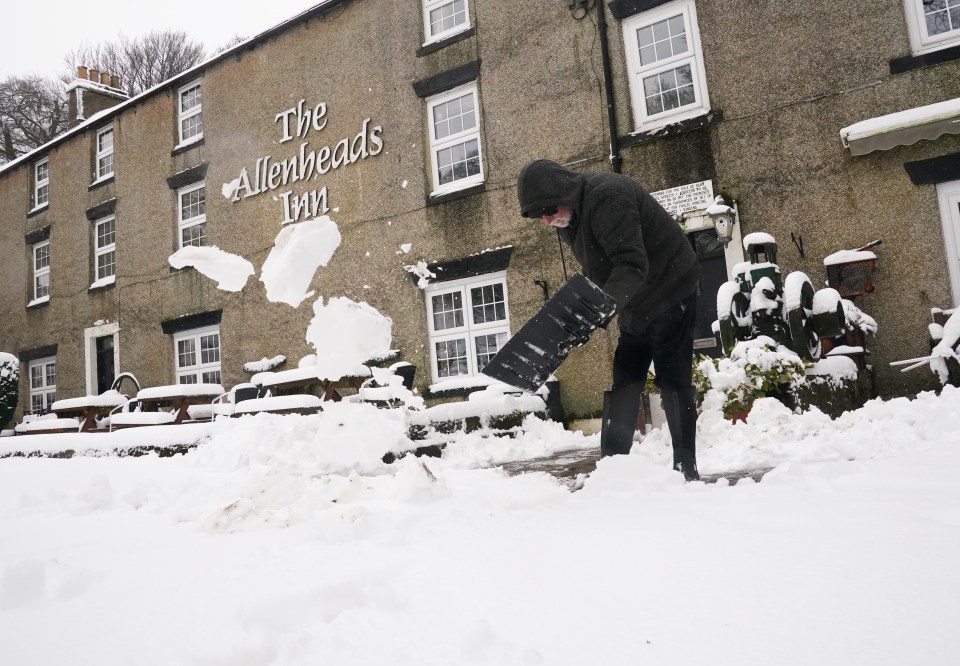 A person clears snow outside The Allenheads Inn in Allenheads, Northumberland on February 9