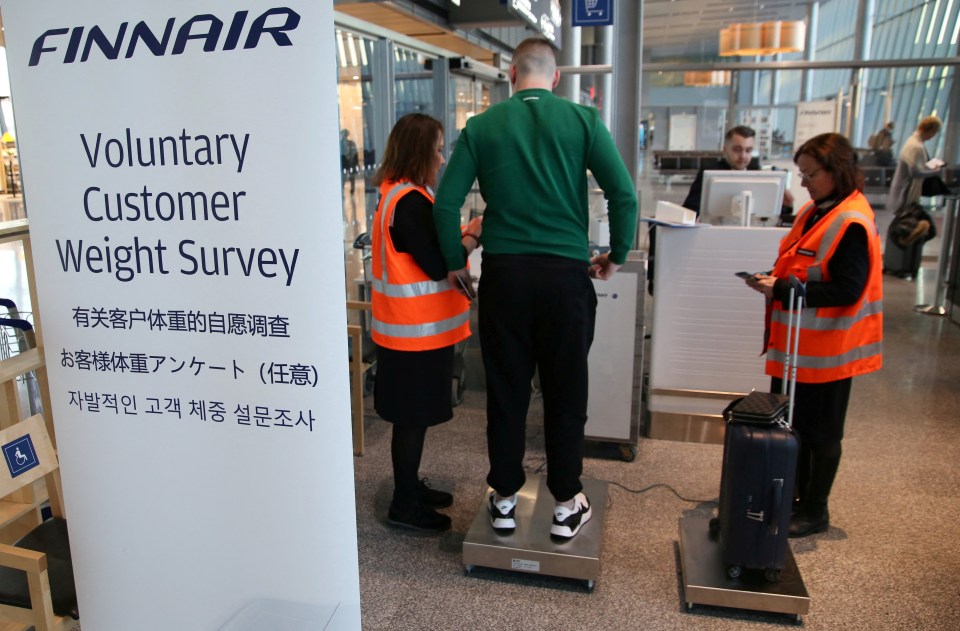 A FinnAir passenger is weighed before boarding