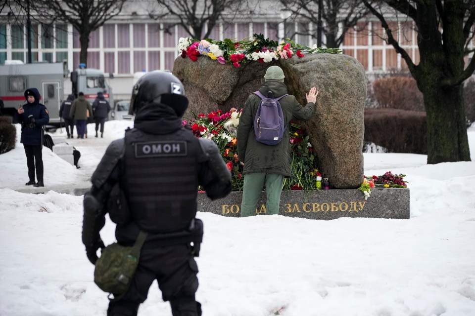 Cops kept a close eye on a man as he lays flowers on a makeshift Alexei Navalny monument