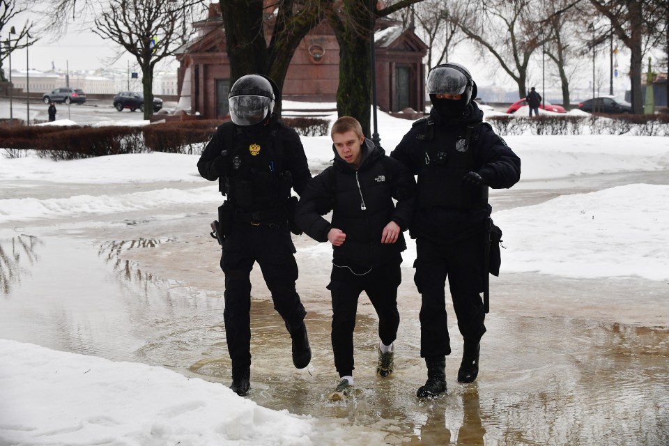 Police officers detain a man as people come to the monument to the victims of political repressions to lay flowers for late Russian opposition leader