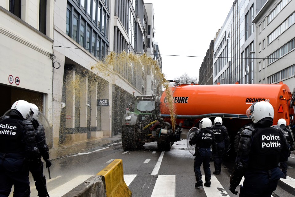 Police are sprayed by manure during a farmers demonstration in the European Quarter outside a meeting of EU agriculture ministers in Brussels, Monday