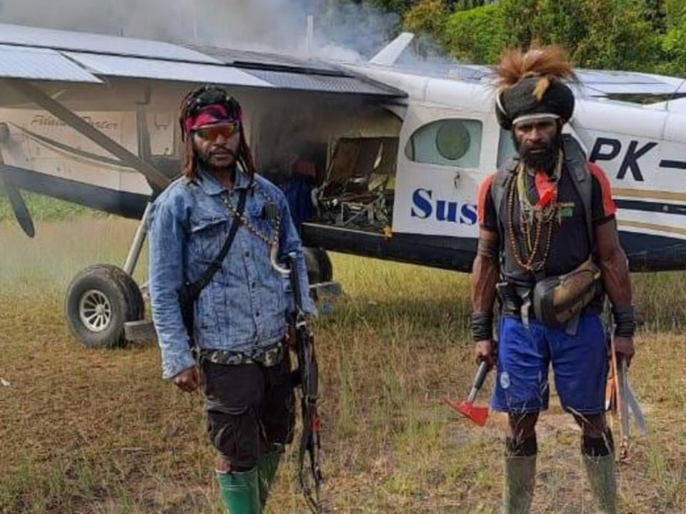 The rebels pose with the captured airplane as they set it on fire