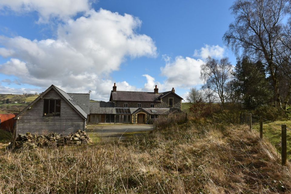 The house sits on "nestled hills" and features a "sweeping drive and large barn."