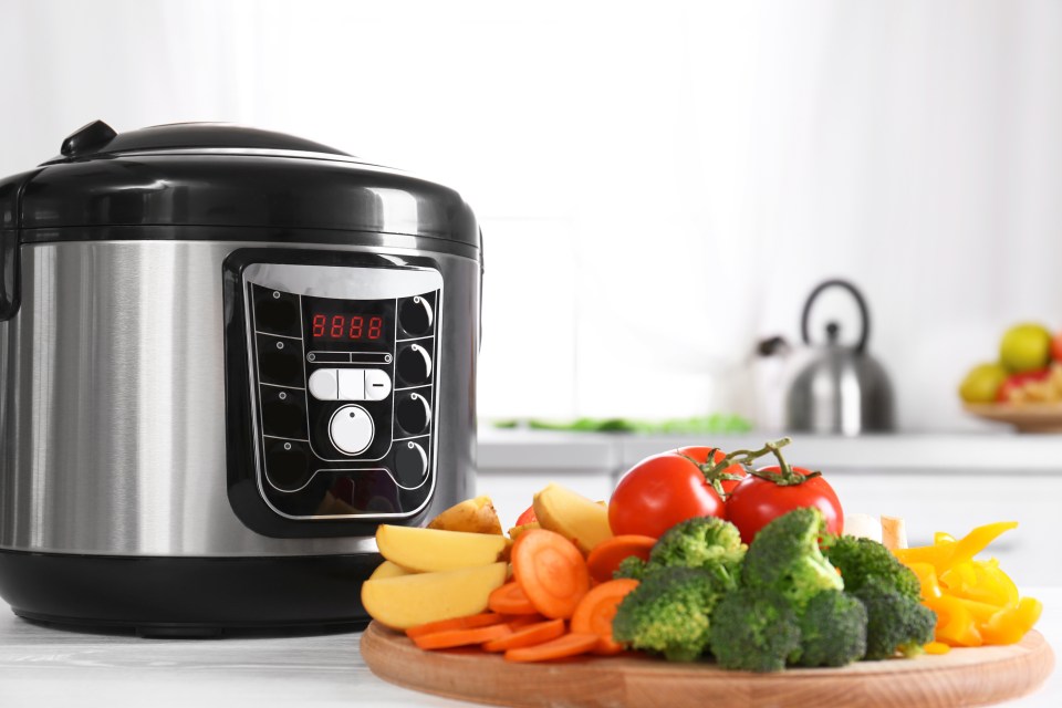 Modern multi cooker and wooden board with vegetables on white table in kitchen; Shutterstock ID 1452485291; purchase_order: -; job: -; client: -; other: -