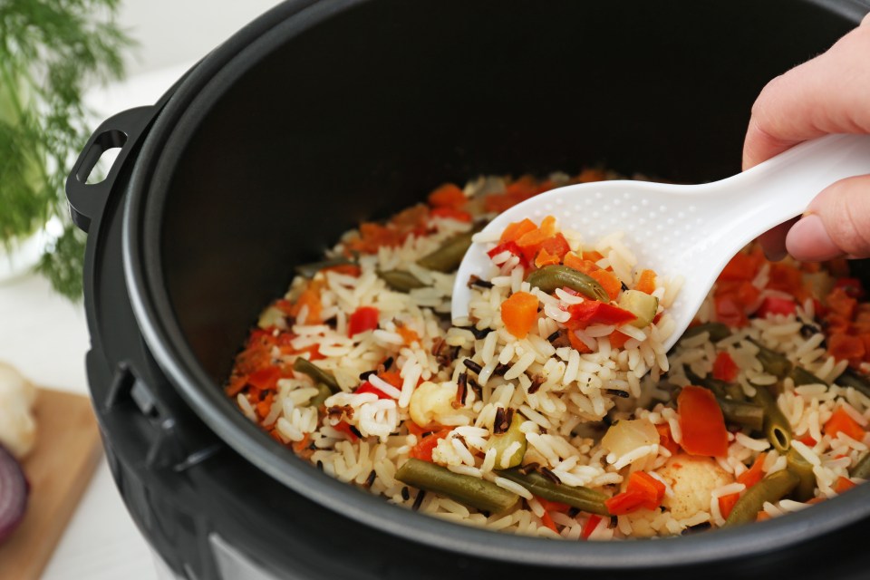 Woman preparing rice with vegetables in multi cooker, closeup; Shutterstock ID 1463786672; purchase_order: -; job: -; client: -; other: -