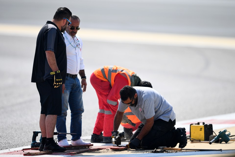 Track workers attempt to fix the loose drain cover that caused a red flag delay