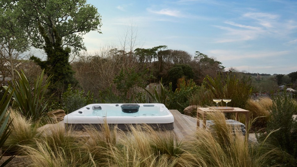 a hot tub is surrounded by tall grass and trees