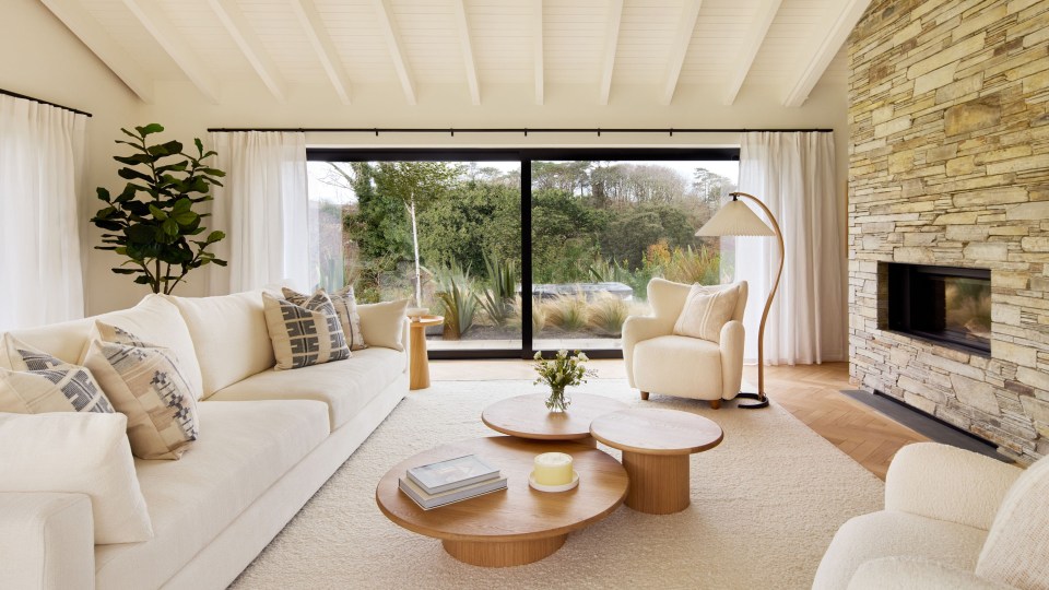 a living room with white furniture and a fireplace