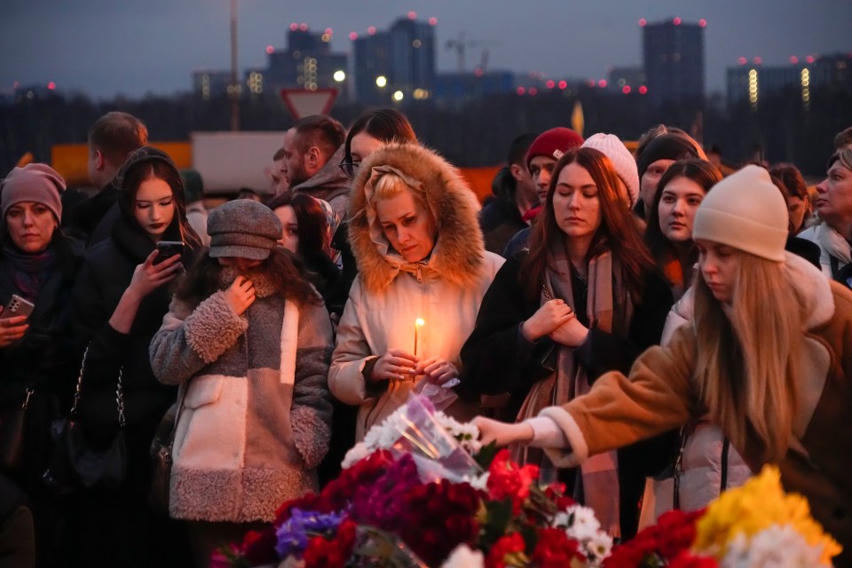 Russian mourners attend a makeshift memorial outside the scene of the slaughter