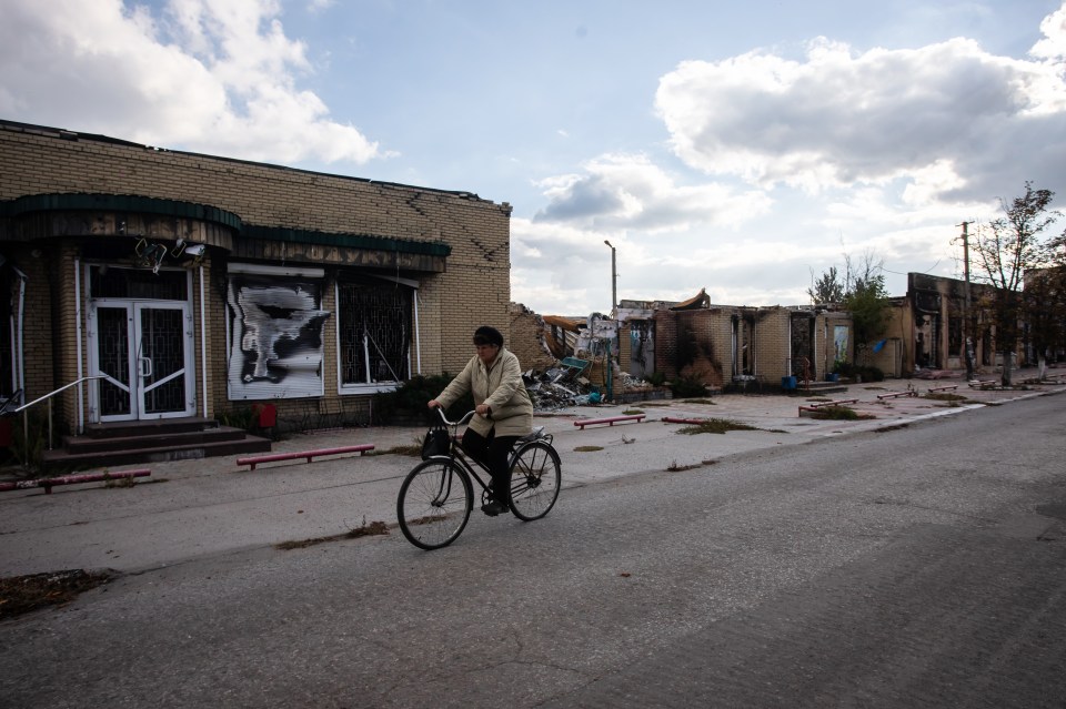 A woman rides a bicycle through Liman the same month the town is liberated