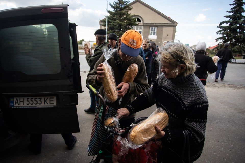 A couple packs bread they received during distribution of aid in Liman in October 2022