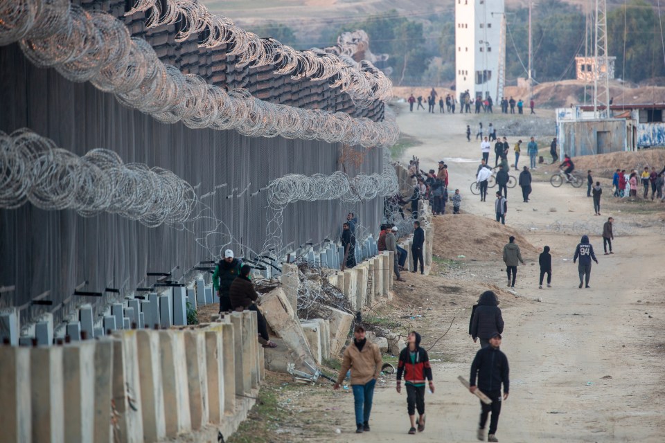 Displaced Palestinians walk near the Palestinian-Egyptian border in the Rafah refugee camp