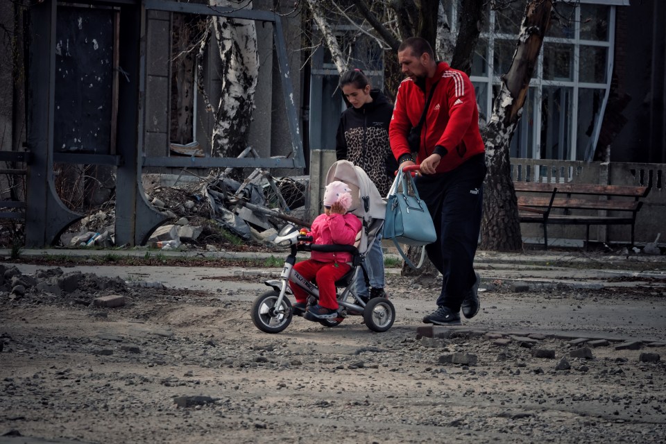 Locals walk through the rubble of a damaged street in Liman