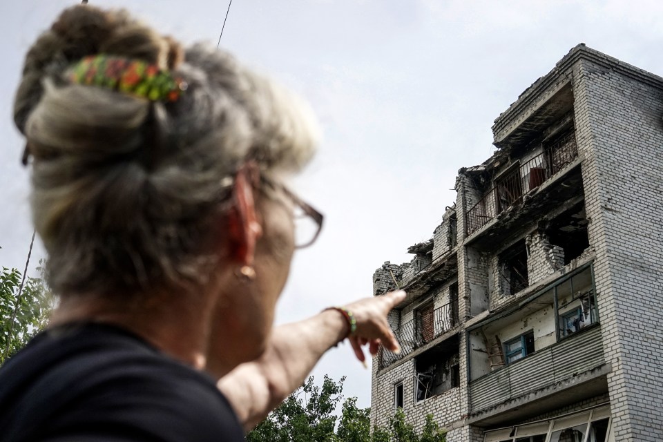 A local woman points to her apartment destroyed by a Russian missile strike