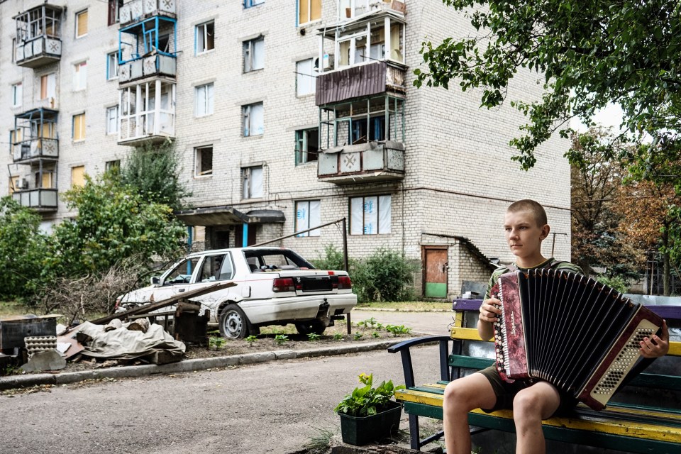 Fedir, 14, plays the accordion outside his home in Liman, Ukraine