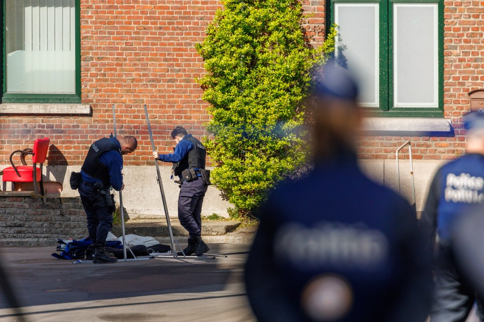 Belgian police officers stand guard outside the house where the attack took place