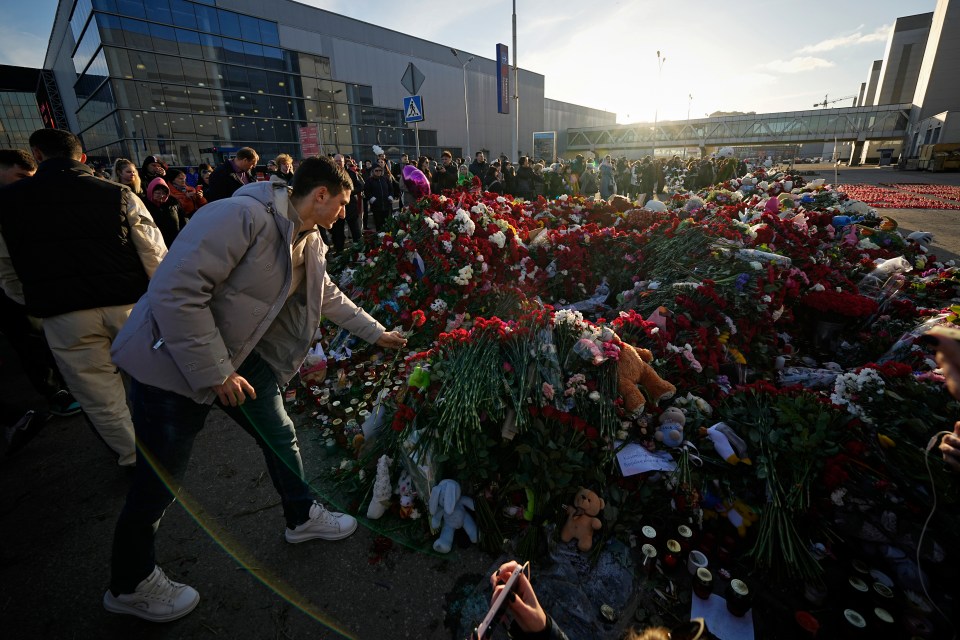 People place flowers at a makeshift memorial in front of the Crocus City Hall on Monday