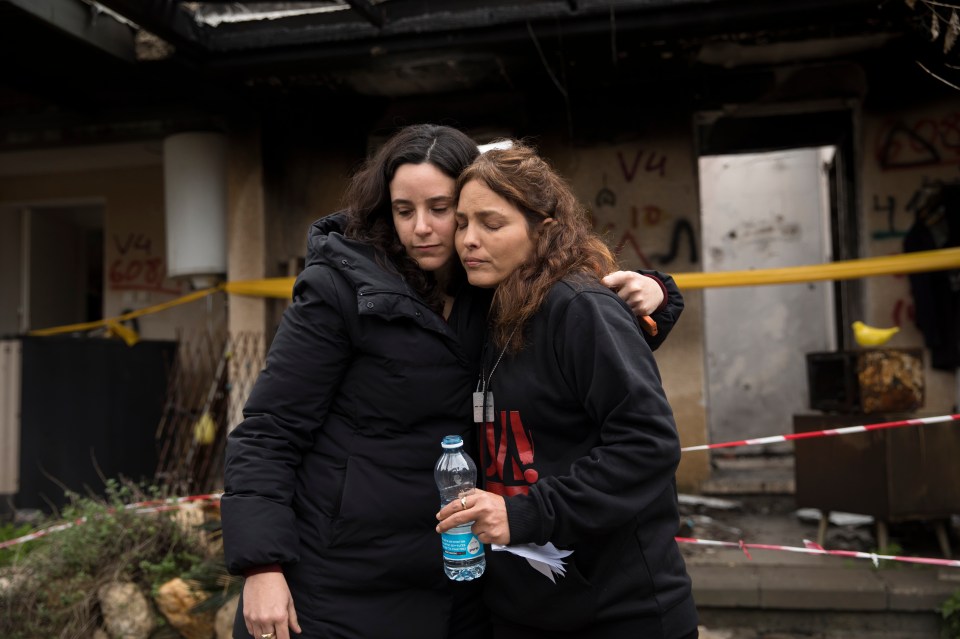 A friend consoles her outside her home in Kfar Aza, Israel