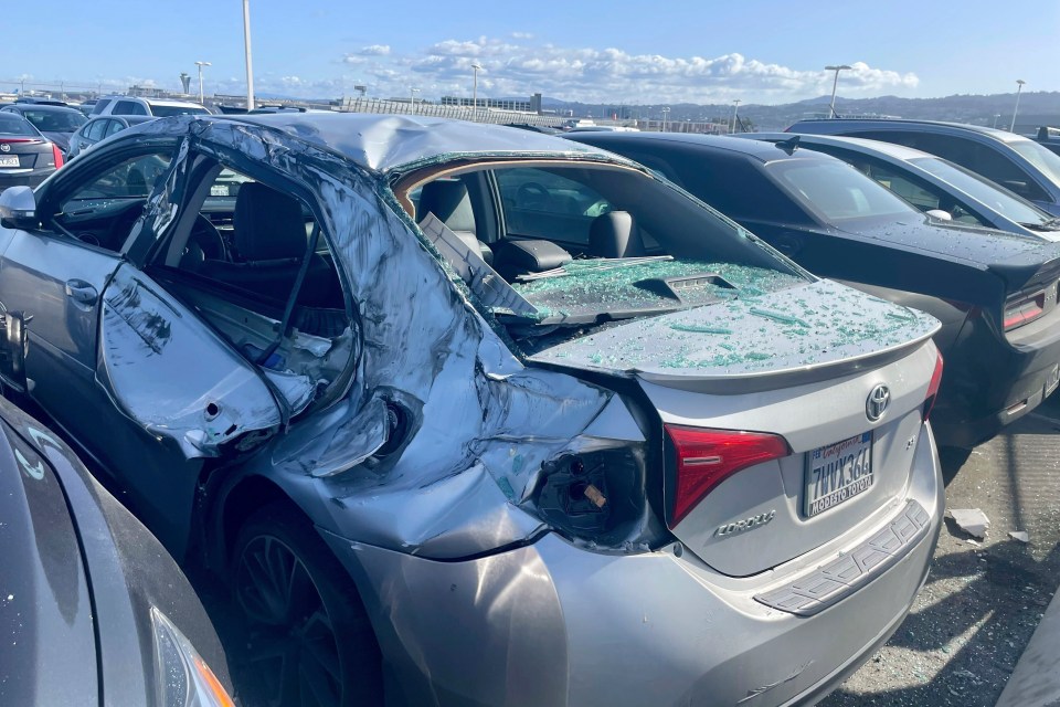 A damaged car is seen in an airport parking lot after a tyre fell from the sky