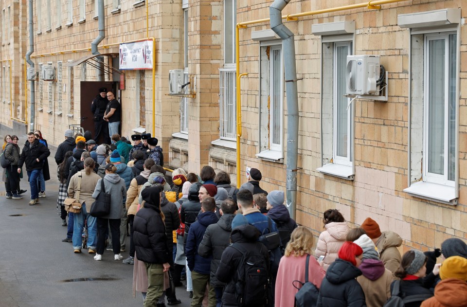 People stand in a line to enter a polling station around noon on the final day of the presidential election in Moscow