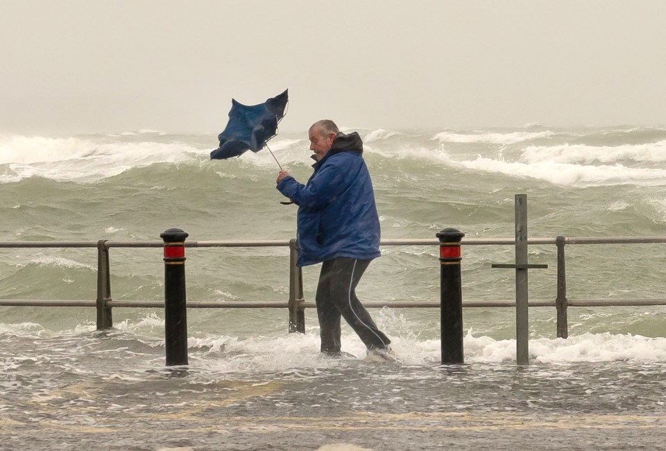 Someone struggles yesterday with an umbrella on Mudeford Quay seafront in Dorset