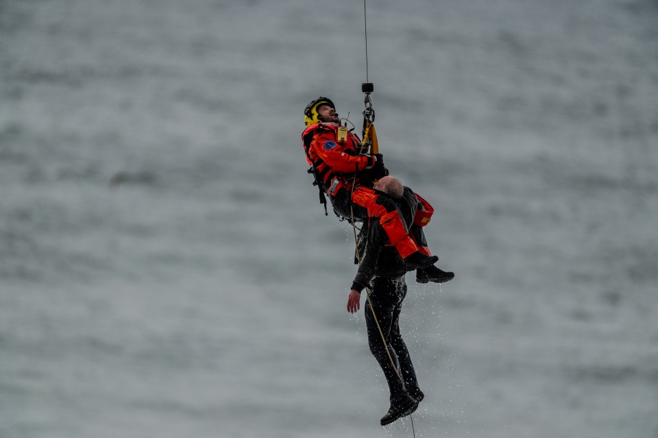 Footage shows the man being winched to safety as his dog was left on the beach below