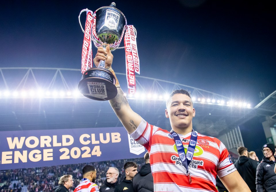 A Wigan Warriors player lifts the Betfred World Club Challenge trophy.